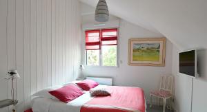 um quarto com uma cama com lençóis cor-de-rosa e uma janela em Chez Lilette em La Baule