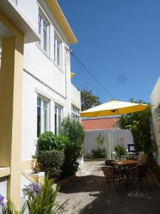 eine Terrasse mit einem Tisch und einem Sonnenschirm in der Unterkunft Casa Londres in Estoril