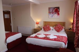 a hotel room with two beds with red pillows at Bournemouth Sands Hotel in Bournemouth +37 photos