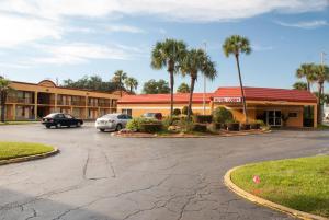 a hotel with two cars parked in a parking lot at Scottish Inn Downtown Jacksonville in Jacksonville