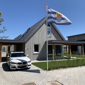 um carro estacionado em frente a um edifício com uma bandeira em Casa Bos Schotsman Wellness em Kamperland