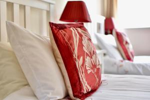 a red pillow sitting on top of a bed with pillows at Witchingham B&B in Holyhead
