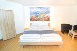 a white bed in a room with a painting on the wall at W-Apartments - Spacious Parking, EV-Station, Washer & Private Garden in Offenburg