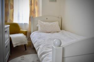 a small bedroom with a white bed and a chair at Witchingham B&B in Holyhead
