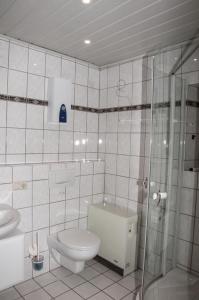 a white tiled bathroom with a toilet and a shower at Ferienhaus an der Mosel in Senhals