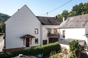 a white house with a porch and a balcony at Ferienhaus an der Mosel in Senhals