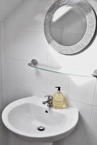 a bathroom sink with a mirror and a soap dispenser at Witchingham B&B in Holyhead