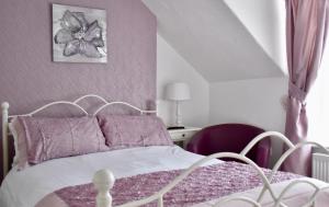 a bedroom with a white bed with purple pillows at Witchingham B&B in Holyhead