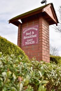 a sign on top of a brick building at Witchingham B&B in Holyhead