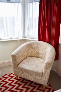 a white chair sitting in a room with windows at Witchingham B&B in Holyhead