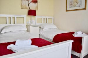 two twin beds in a room with red and white sheets at Witchingham B&B in Holyhead