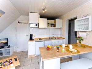 eine Küche mit weißen Schränken und einer hölzernen Arbeitsplatte in der Unterkunft FeWo Sonnenanbeter in Dorum