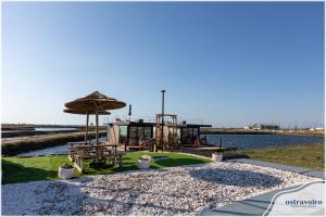 a park with a playground and an umbrella and water at Barcos Casa OstrAveiro in Aveiro