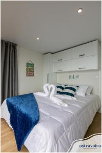 a bedroom with a large white bed with blue and white sheets at Barcos Casa OstrAveiro in Aveiro