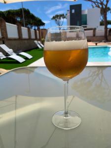 un vaso de cerveza sentado en una mesa junto a una piscina en La Quinta - La Barrosa, en Chiclana de la Frontera