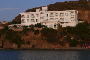a large white building on a hill next to the water at E.J. Pyrgos Bay Hotel in Kato Pyrgos