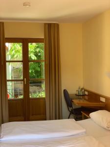 a hotel room with a bed and a desk and a window at Hotel Erlenbacher Hof in Bad Homburg vor der Höhe
