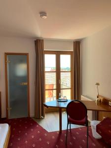 ein Hotelzimmer mit einem Tisch, einem Bett und einem Fenster in der Unterkunft Hotel Erlenbacher Hof in Bad Homburg vor der Höhe
