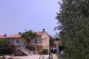 a large yellow house with a tree in front of it at Apartments Nella in Sveti Anton