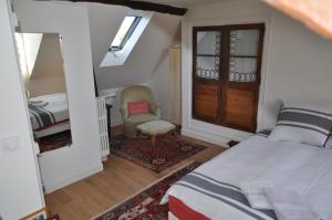 a bedroom with a bed and a chair and a window at La passerelle in Combleux