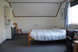 een slaapkamer met een bed, een wastafel en een raam bij De strandkamer in Oostkapelle