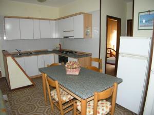 eine Küche mit einem Tisch mit Stühlen und einem Kühlschrank in der Unterkunft Villa Milviana appartamento in Rosolina Mare