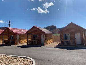 a row of wooden cabins with mountains in the background at Red Canyon Cabins in Kanab