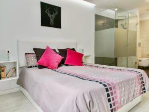una camera da letto con un grande letto con cuscini rosa di The Cool Apartment a Puerto de la Cruz