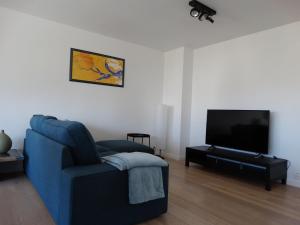 a living room with a blue couch and a flat screen tv at Appartement Ter Duinen - Lux Living in De Panne