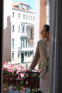 a man in a suit looking out of a window at Locanda Gaffaro in Venice