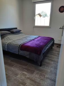 a bedroom with a bed with a purple comforter at Gîte les 2 pins - Audenge in Audenge