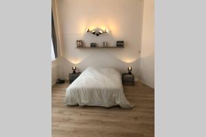 a bedroom with a bed with white sheets and two lamps at joli 2 pieces en centre ville , gare à 50 mètres in Grenoble