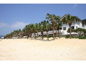 ein Gebäude an einem Strand mit Palmen darauf in der Unterkunft Amami Resort Bashayamamura / Vacation STAY 81475 in Amami