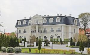 una gran casa blanca con techo negro en Hotel Toscania, en Włoszakowice