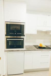 a kitchen with white cabinets and a microwave at GROS ZURRIOLA BEACH WIFI TERRACE PARKING 20E night in San Sebastián
