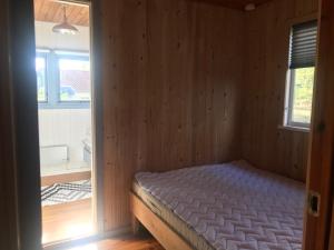a bedroom with a bed in a wooden room at Hyggeligt sommerhus i Ebeltoft, tæt på strand og skov. in Ebeltoft