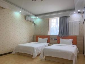 um quarto com 2 camas e uma janela em 7Days Premium Beijing Gulou em Pequim