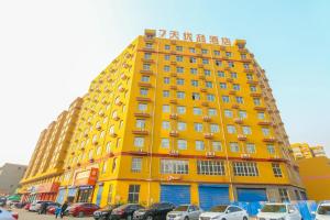 a yellow building with cars parked in a parking lot at 7 Days Premium Linfen Pingyang South Street Branch in Linfen
