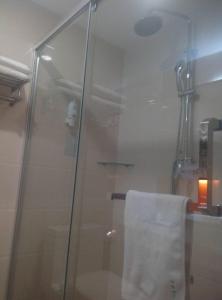 a shower with a glass door and a towel at 7 Days Premium Linfen Pingyang South Street Branch in Linfen