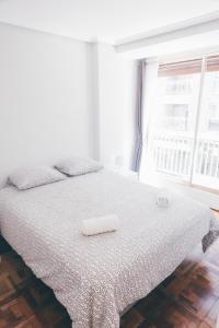 1 dormitorio con 1 cama con colcha blanca y ventana en GROS ZURRIOLA BEACH WIFI TERRACE PARKING 20E night, en San Sebastián