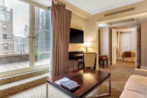 ニューヨークにあるオムニ バークシャー プレイスのベッドデスク、大きな窓が備わるホテルルームです。