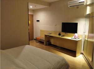 um quarto de hotel com uma cama e uma secretária com uma televisão em 7Days Premium Guyuan Beijing Road Branch em Guyuan