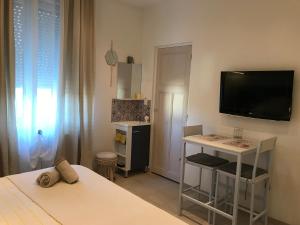 - une chambre avec un lit et une télévision murale dans l'établissement Le Marty, à Narbonne