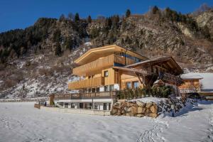 un edificio en la nieve frente a una montaña en Gästehaus Haus Barbara, en Neustift im Stubaital