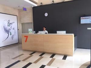 7Days Premium Shijiazhuang Luquan Shangzhuang Branch في هيبي: امرأة تجلس في مكتب الاستقبال في مكتب