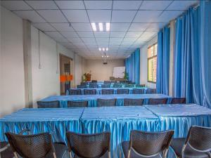 昆明市にある7Days Premium Kunming New Asia Sports City Subway Station Branchの青いテーブルと椅子、青いカーテンが備わる客室です。