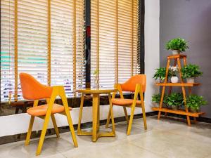 dos sillas naranjas y una mesa frente a una ventana en 7Days Premium Chenzhou Guoqing South Road Branch, en Chenzhou