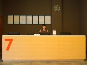 a woman sitting at a reception desk with a laptop at 7Days Premium Leshan Qianwei Fengye Fortune Center Branch in Leshan
