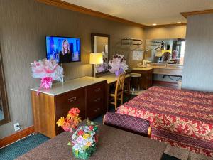 um quarto de hotel com uma cama e uma televisão em New Century Inn em San Gabriel