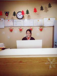 Shihezi的住宿－7天优品石河子开发区店【高端经济型酒店】，女人站在桌子后面,电脑